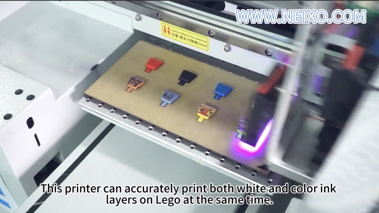 Several Lego torsos arranged on a UV printer bed while the printer head cures and prints them.